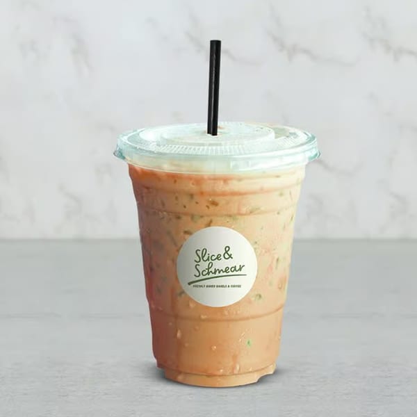 Iced coffee with a Slice & Schmear logo on the cup, against a light marble background.